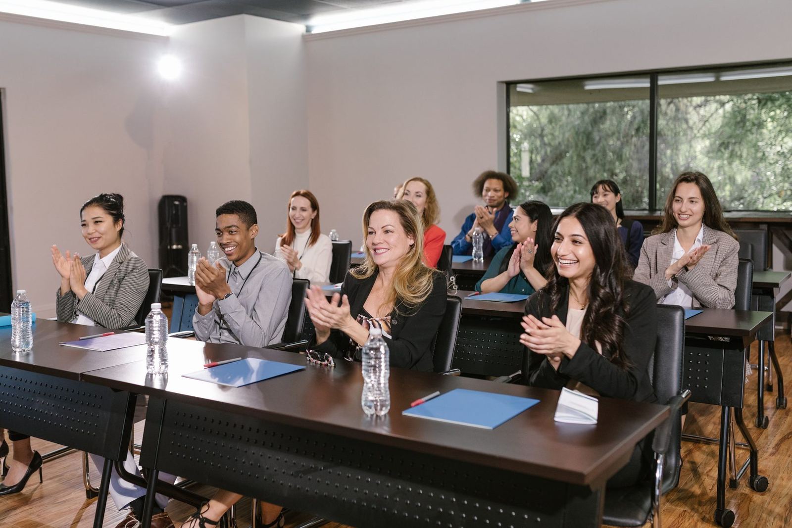 Plateia sentada num seminário, sorrindo e aplaudindo